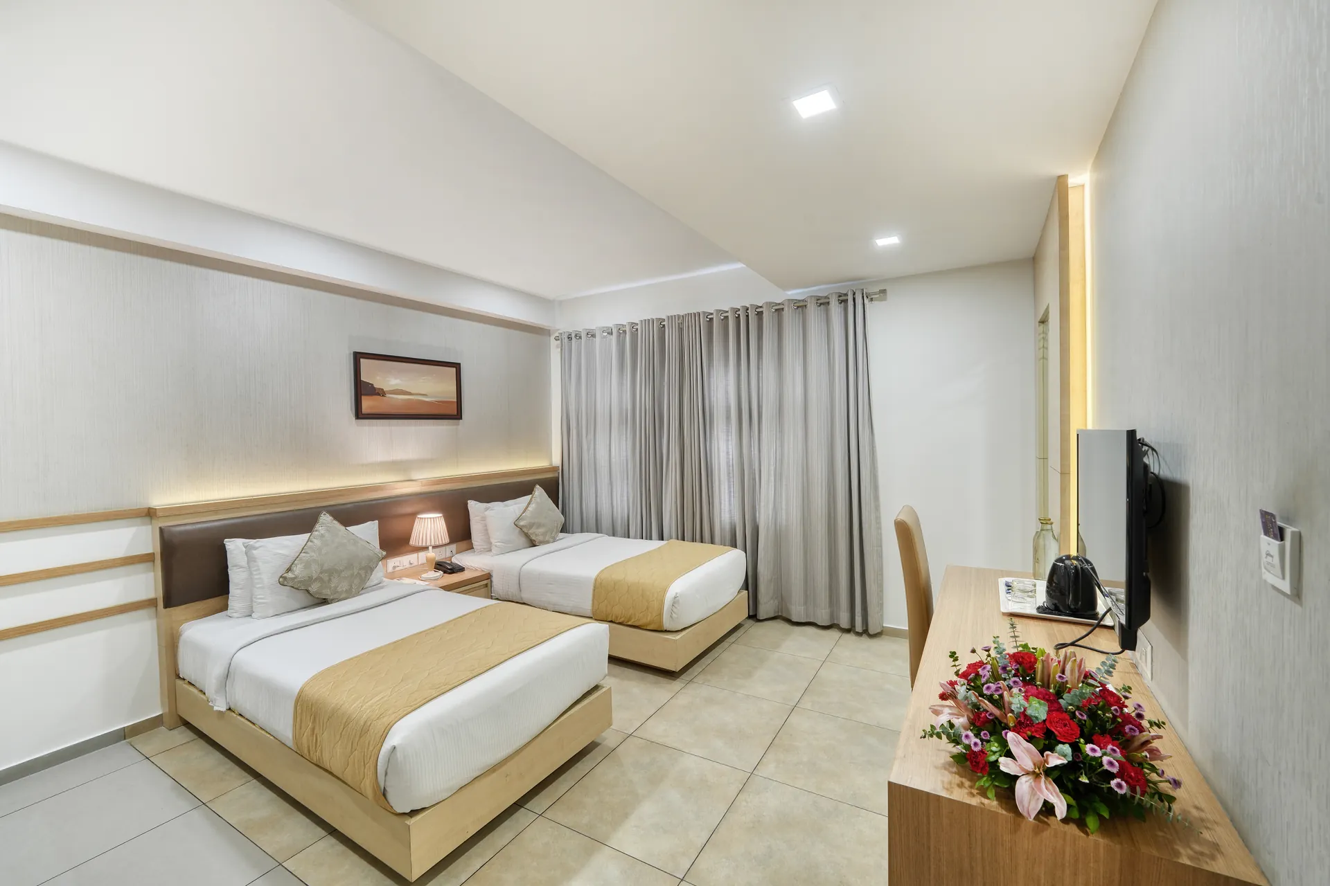 Banglore Hotel twin bedroom with matching beds, grey drapes and fresh flower arrangement — hotel properties shot in Kochi, Kerala, Bengaluru (Bangalore)