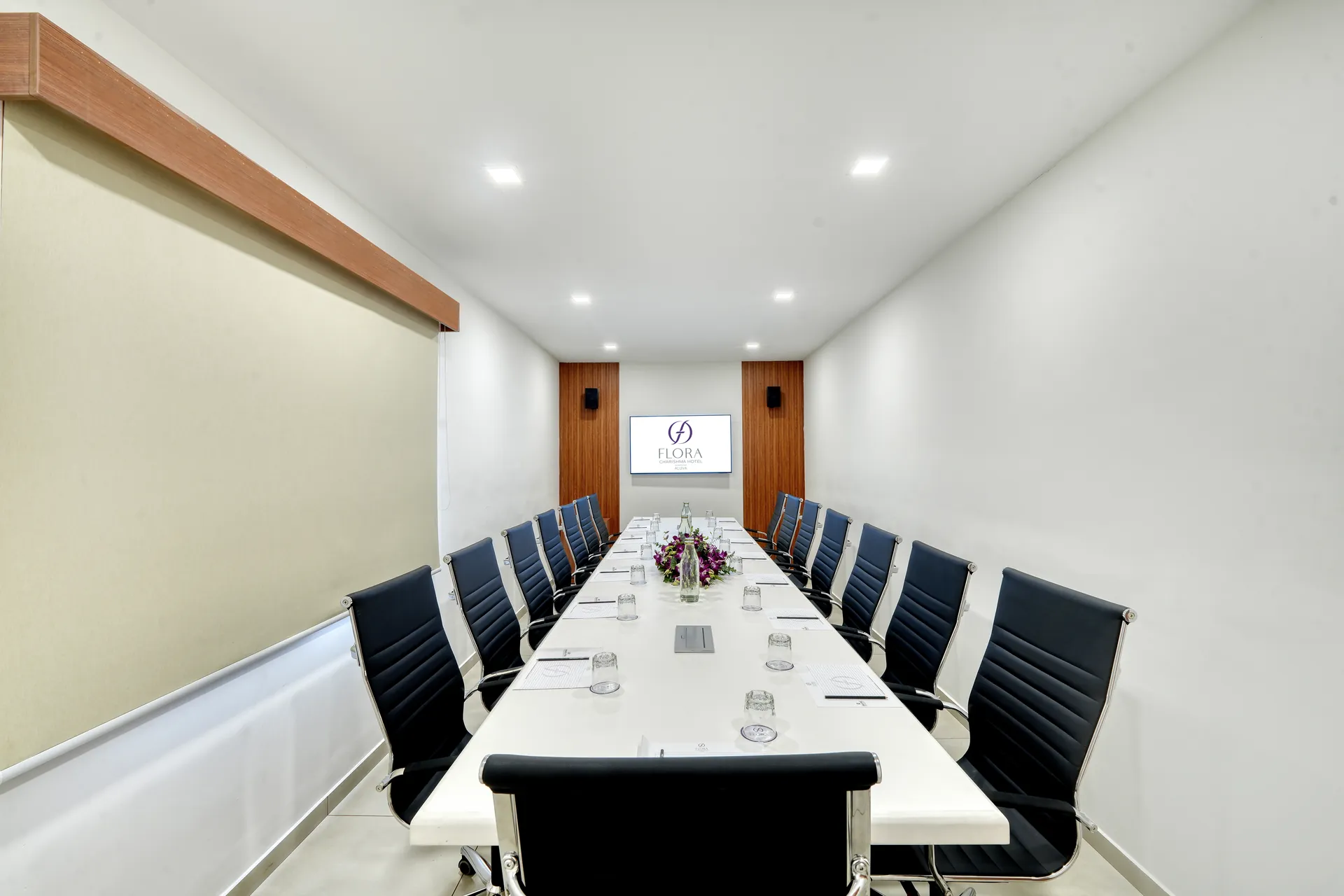 Bengaluru Hotel meeting room with long white table, executive chairs and branded display screen — hotel properties shot in Kochi, Kerala, Bengaluru (Bangalore)