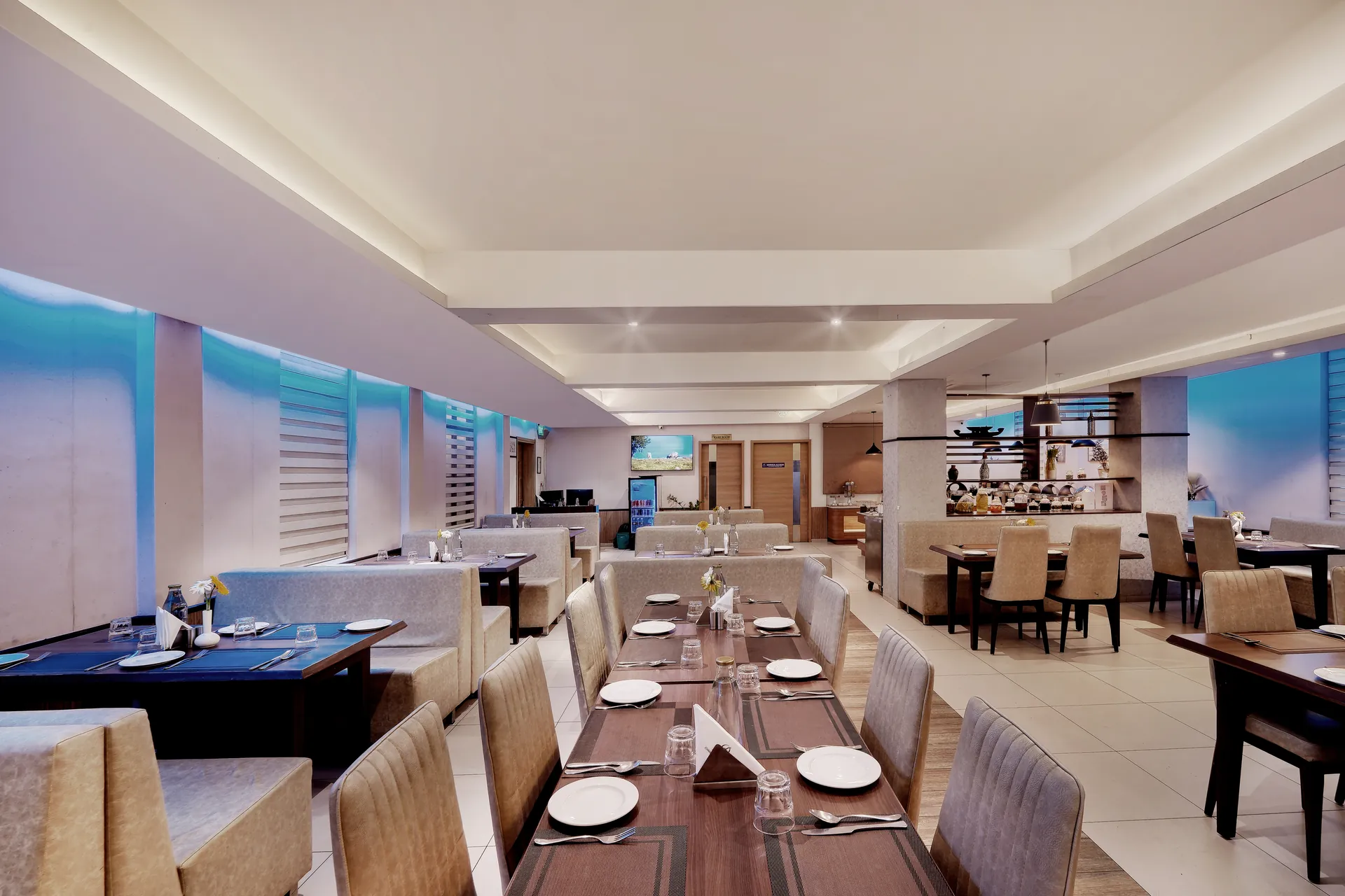 Hotel dining hall with set tables, banquette seating and cove lighting — hotel properties shot in Kochi, Kerala, Bengaluru (Bangalore)